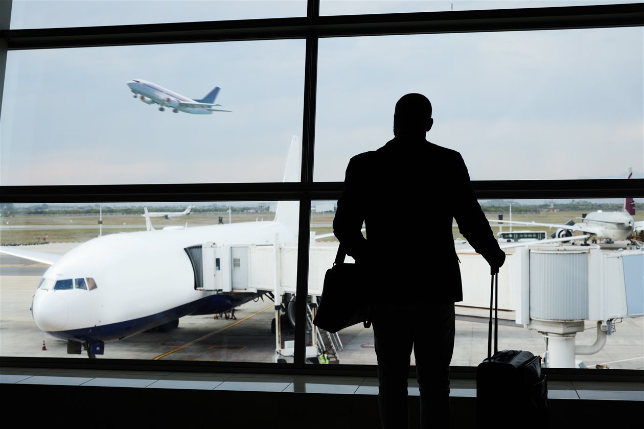 Mann på flyplass som ser ut vindu på fly